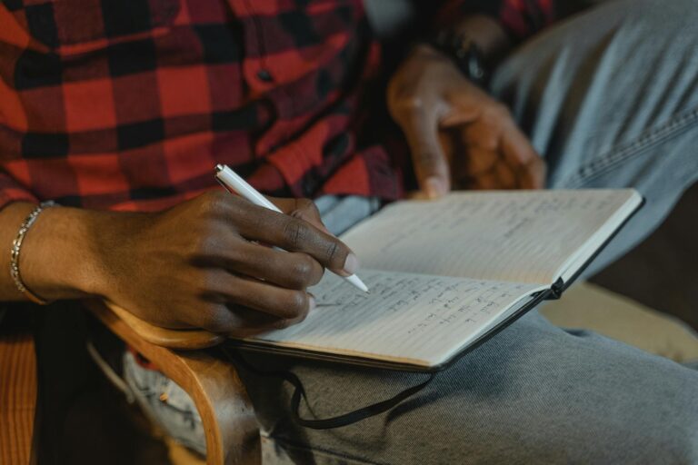Focused close-up of a person writing in a notebook with a pen, capturing a moment of creativity.